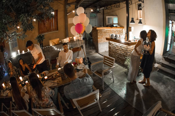 Woman welcoming guest on her birthday dinner party and recieving gifts